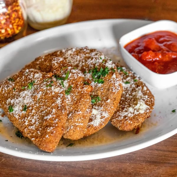 Three breaded chicken cutlets topped with parmesan and parsley, served with a side of marinara sauce.