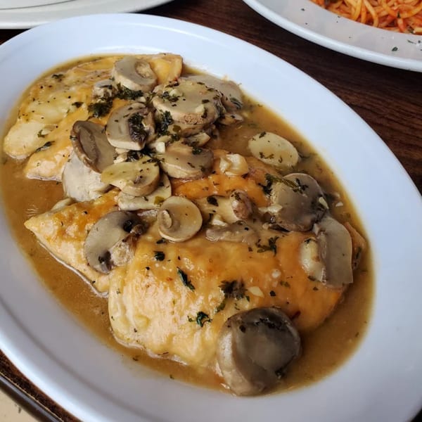Sainato's chicken and mushrooms in a rich, savory sauce on a white plate.