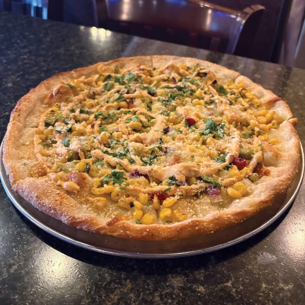 Sainato's at Rivergate pizza with corn, red peppers, and a creamy sauce, garnished with parsley.